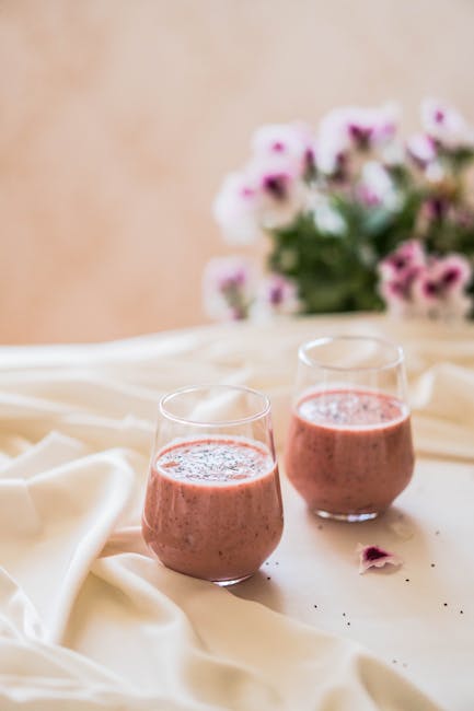 Strawberry smoothies with pansy flowers on a draped cloth, blending elegance with taste.