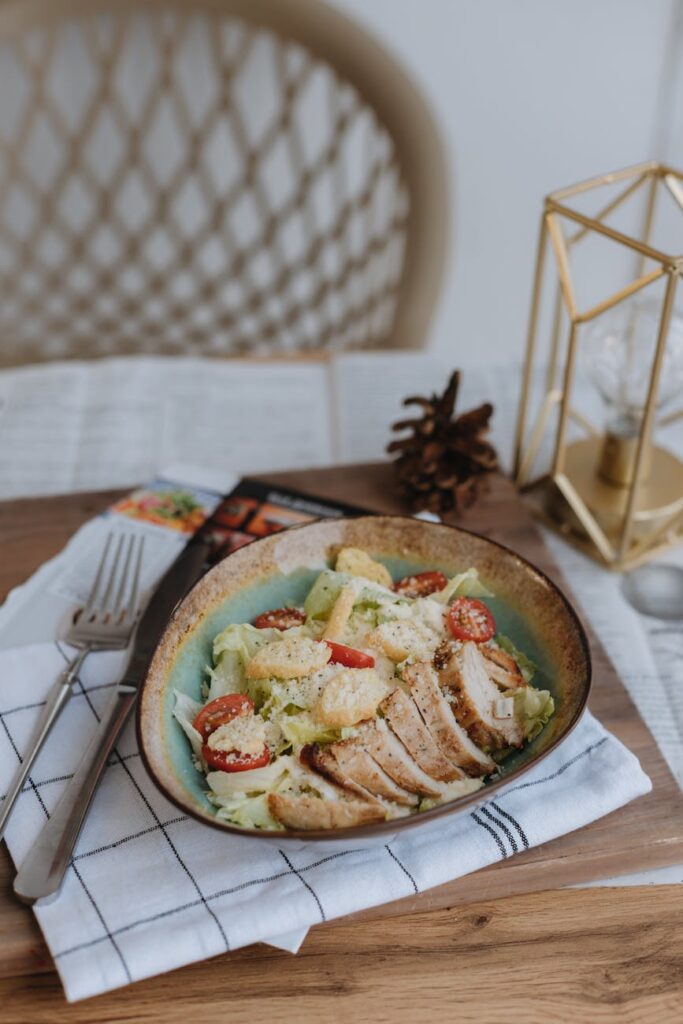 A close-up shot of a Caesar salad with grilled chicken, cherry tomatoes, and parmesan served in a bowl.