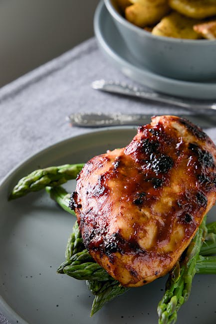 Appetizing grilled chicken breast on asparagus with a side of roasted potatoes. Ideal for food-related content.
