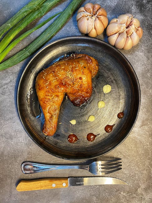 Succulent grilled chicken leg served with garlic cloves, sauce, and fresh herbs for a flavorful meal.