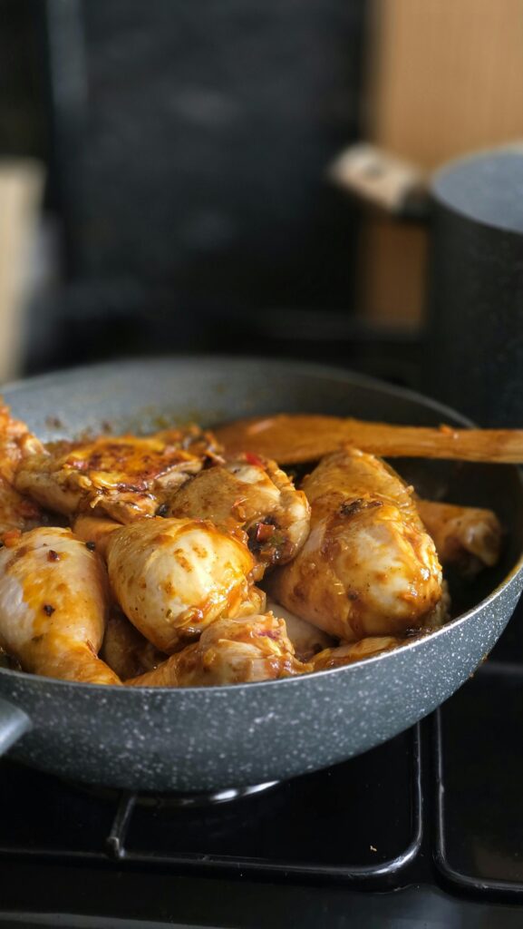 Close-up of seasoned chicken drumsticks cooking in a frying pan, perfect for food blogs.