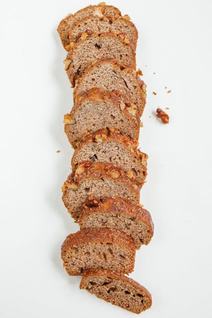 Sliced homemade banana walnut bread arranged vertically on a white background, showcasing its texture and delicious appeal.
