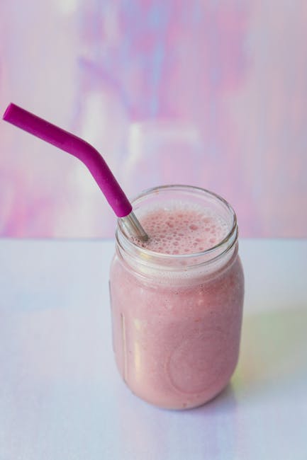Refreshing pink smoothie in a mason jar with a reusable straw, perfect for a healthy snack.